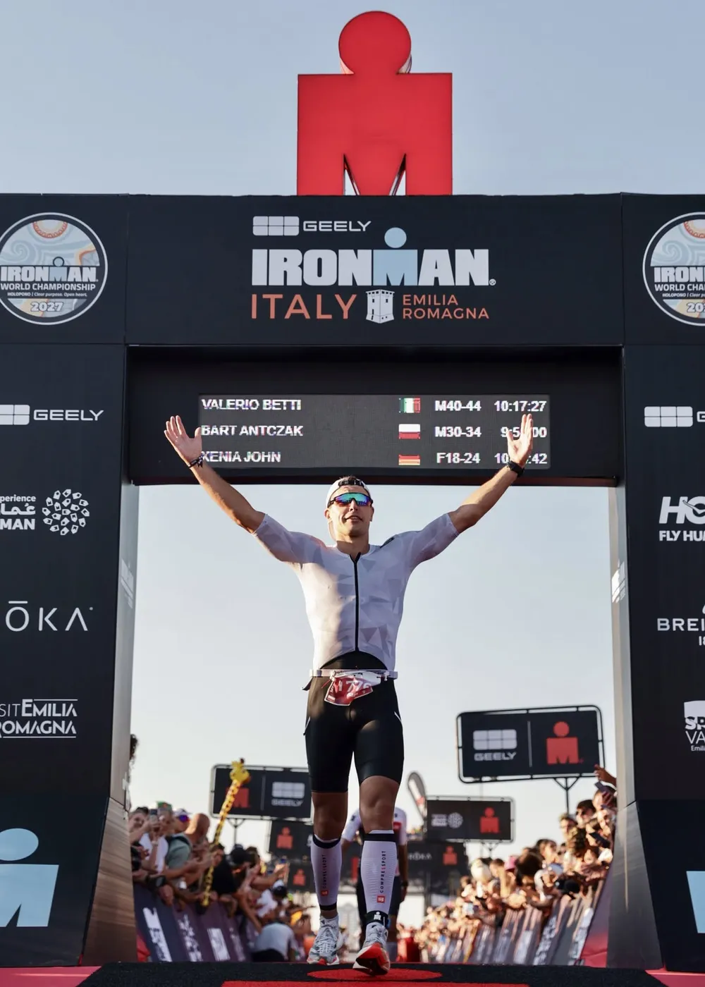 Bart Antczak crossing the IRONMAN Italy Emilia-Romagna finish line with arms raised